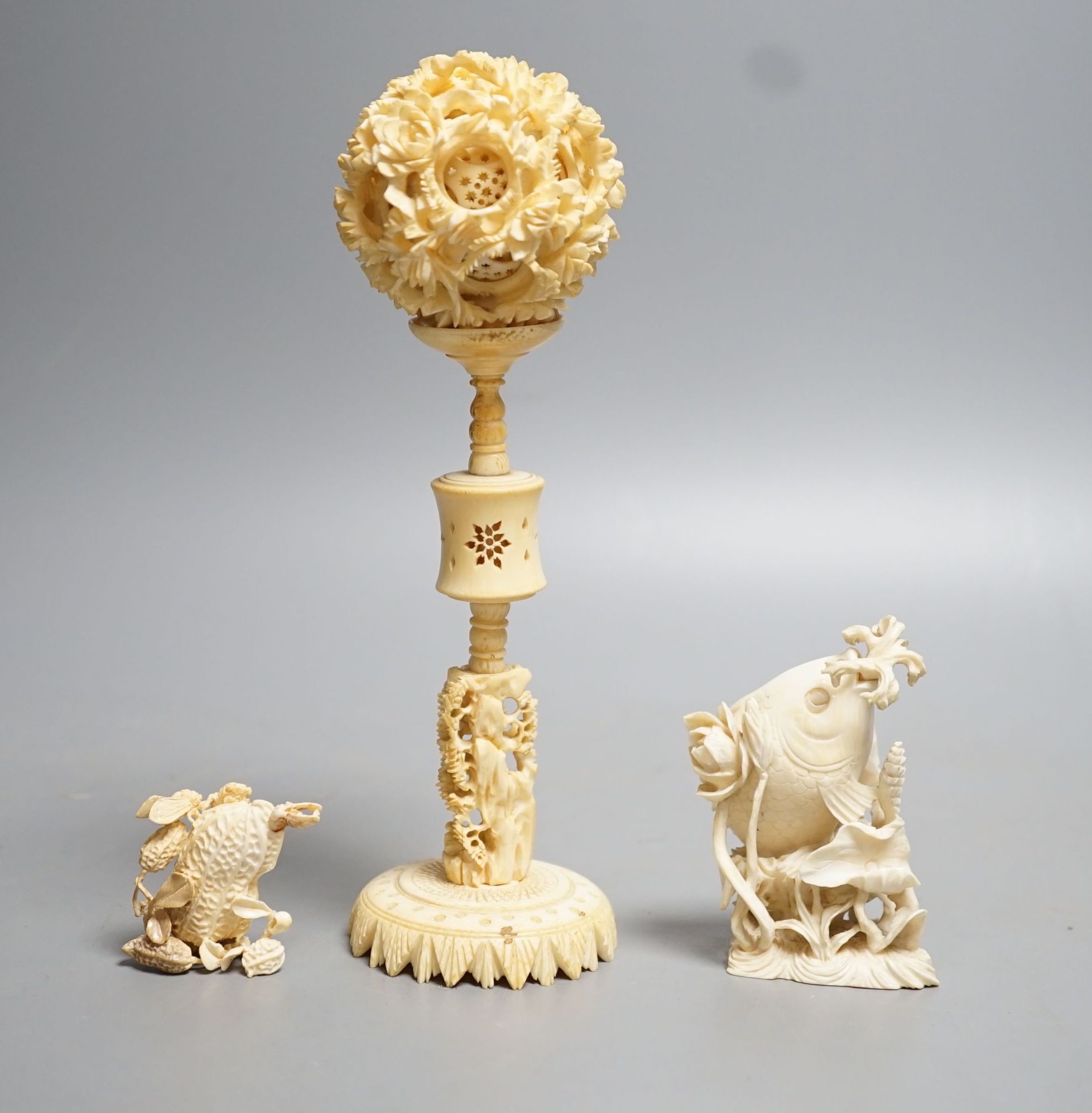 A Chinese ivory concentric puzzle ball and stand, two Chinese ivory snuff bottles and stoppers, modelled as a leaping carp and as cicadas on a nut, early 20th century